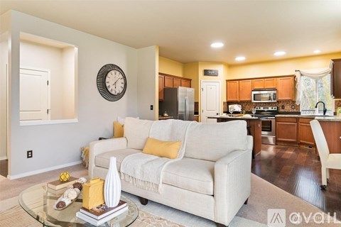 A living room with a white couch and a glass coffee table.