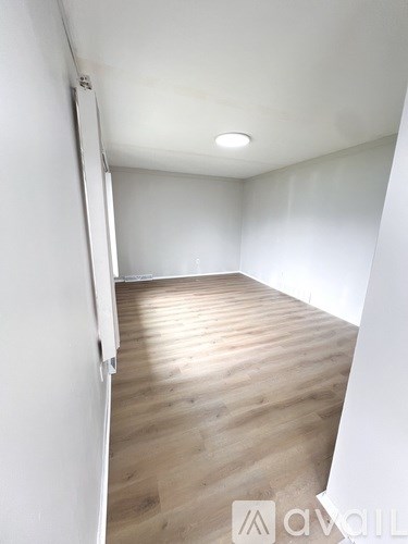 A room with wooden flooring and white walls.