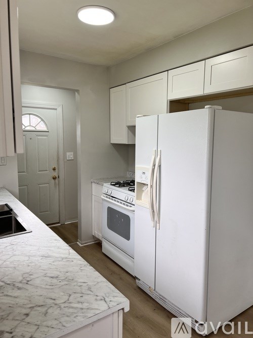 A white kitchen with a refrigerator, oven, and cabinets.
