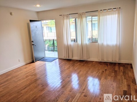 A room with wooden floors and a sliding glass door leading to a balcony.