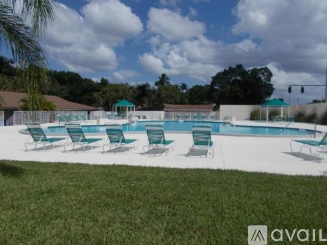A pool with green chairs and a white fence.
