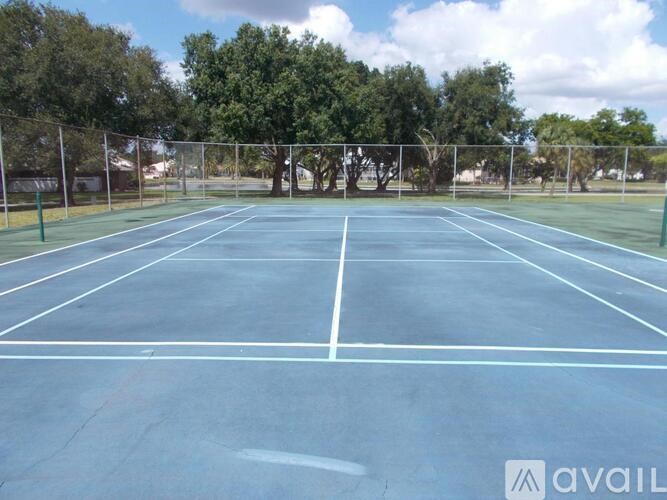 A tennis court surrounded by a fence and trees.