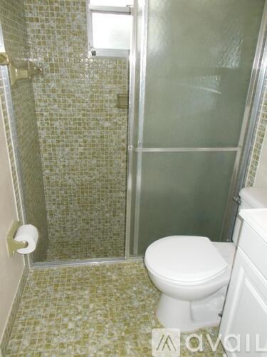 A white toilet in a tiled bathroom with a glass shower door.