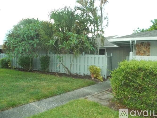 A house with a white picket fence and greenery in front.