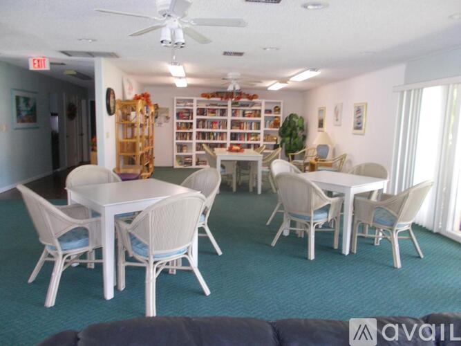 A room with a white table and chairs, a ceiling fan, and a bookshelf filled with books.