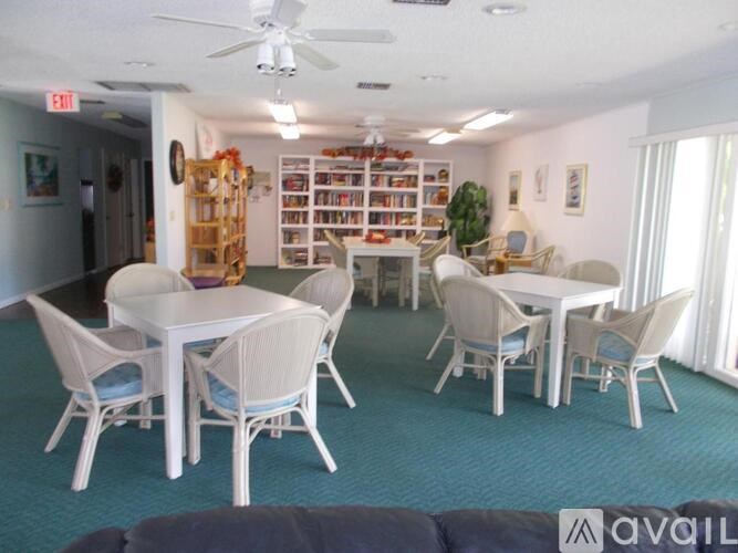A room with a white table and chairs, a ceiling fan, and a bookshelf filled with books.