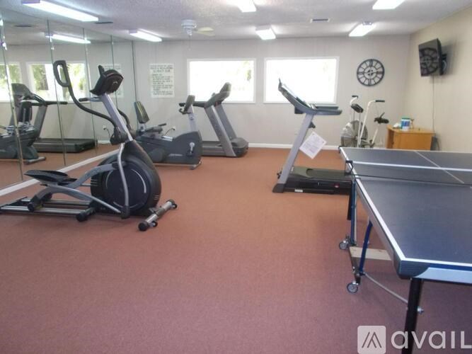 A gym with treadmills, exercise bikes, and a ping pong table.