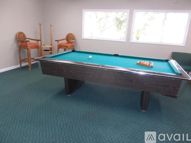 A pool table with a green cloth and a cue stick on it.