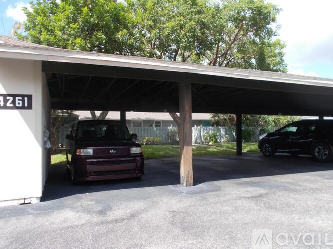 A car is parked under a covered area with the number 261 on the wall.