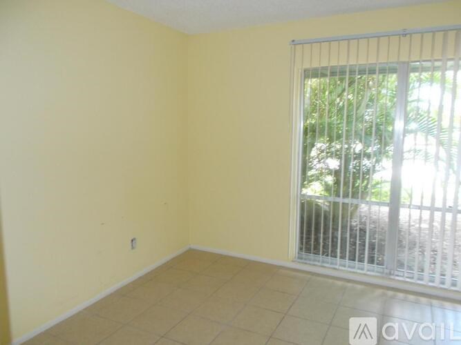 A room with a window and a sliding door leading to a balcony.