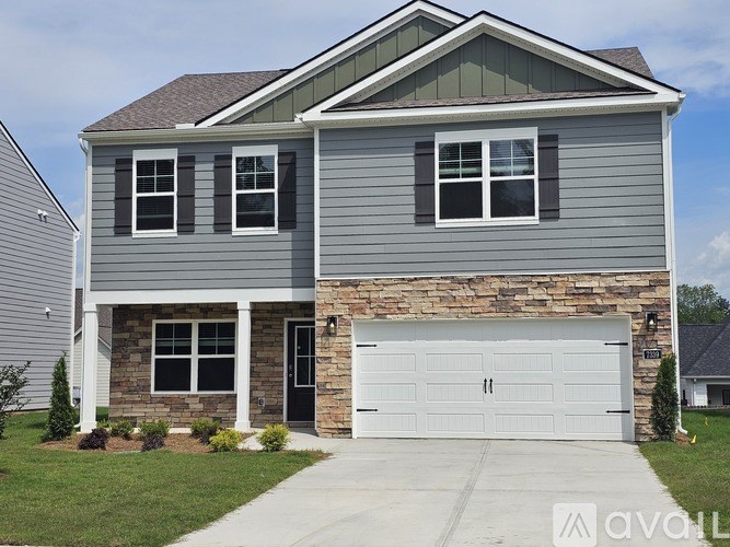 A two-story house with a garage door and a stone wall.
