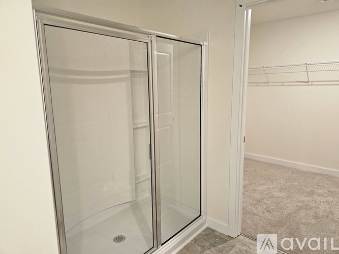 A glass shower stall with a door open to a hallway.