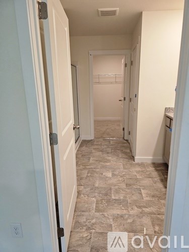 A hallway with tiled flooring and white walls.