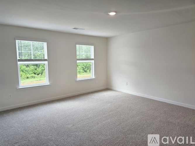 A room with two windows and carpeted floor.