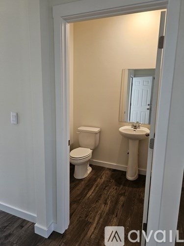 A bathroom with a toilet, sink and mirror.