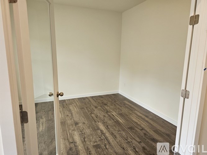 A room with wooden flooring and white walls.
