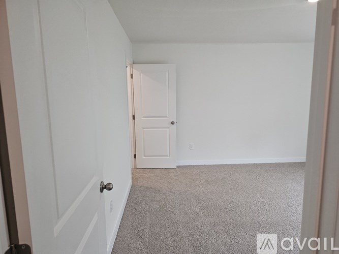 A room with a white door and carpeted floor.