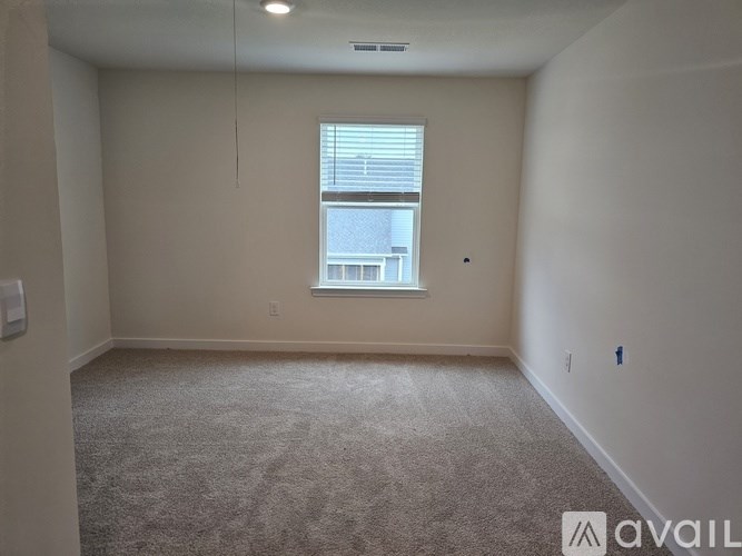 A room with a carpeted floor and a window with blinds.