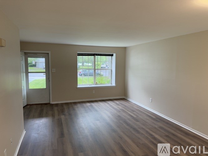 A room with wooden floors and a window overlooking a parking lot.