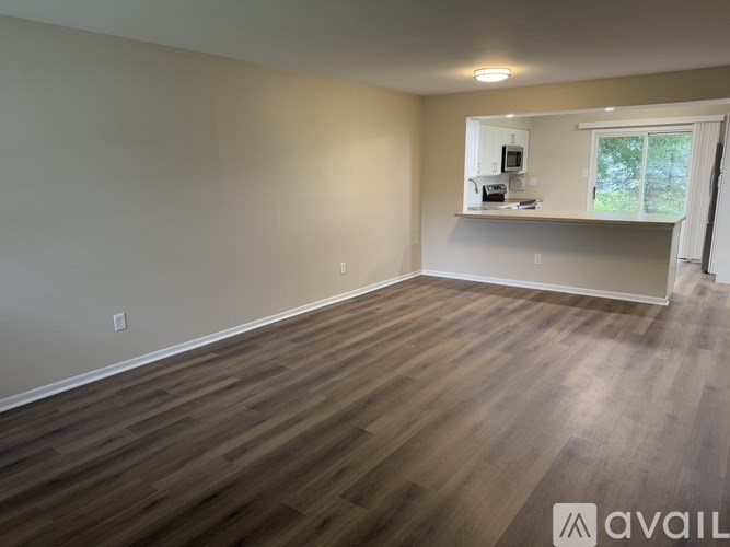 A room with wooden flooring and a window with a view of trees outside.