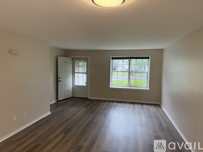 A room with wooden floors and a window showing a green lawn outside.