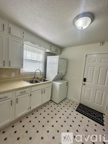 A kitchen with white cabinets and a black and white floor.