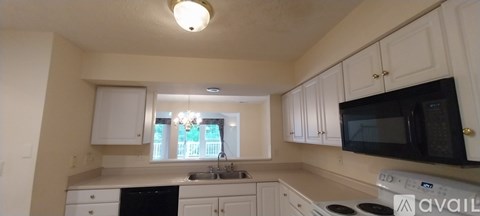 A kitchen with white cabinets and black appliances.
