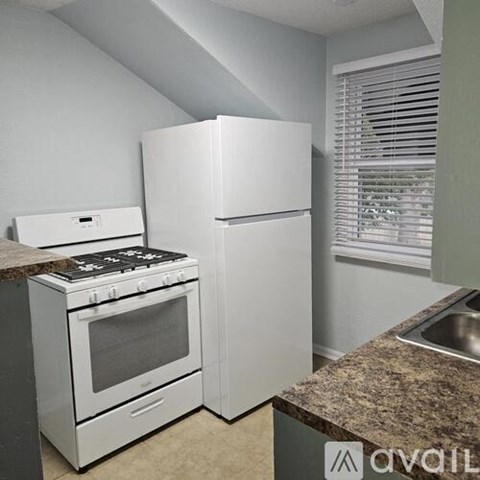 A kitchen with a white stove and refrigerator.