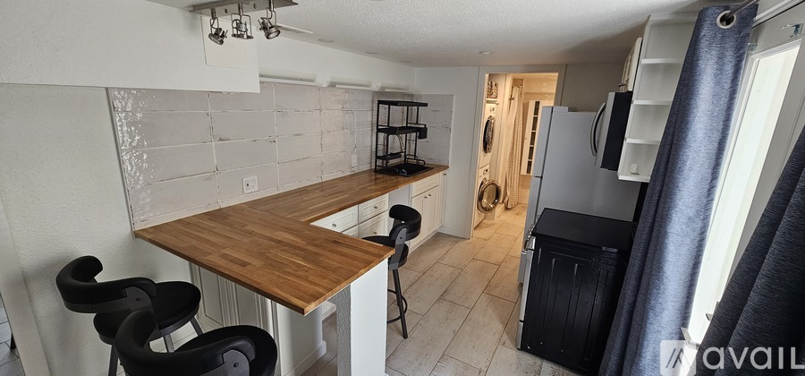 A kitchen with a wooden counter and black chairs.