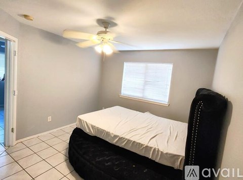 A bedroom with a black bed and a ceiling fan.