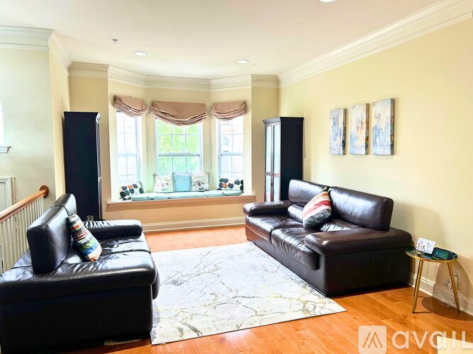 A living room with black leather furniture and a large window.