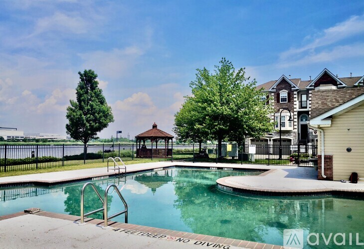 A swimming pool with a diving board and a gazebo in the background.