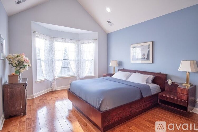 A bedroom with a large bed and a wooden dresser.