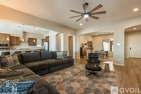 A living room with a brown couch and a ceiling fan.