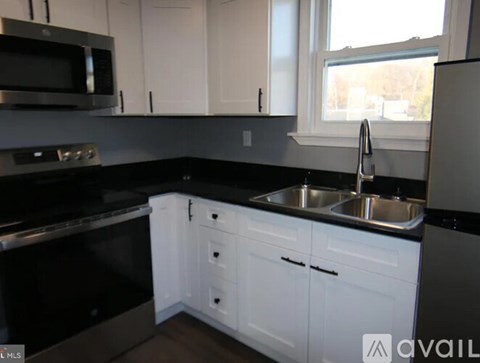 A kitchen with white cabinets and a black countertop.