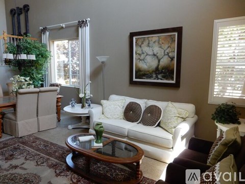 A living room with a white couch, a coffee table, and a painting on the wall.
