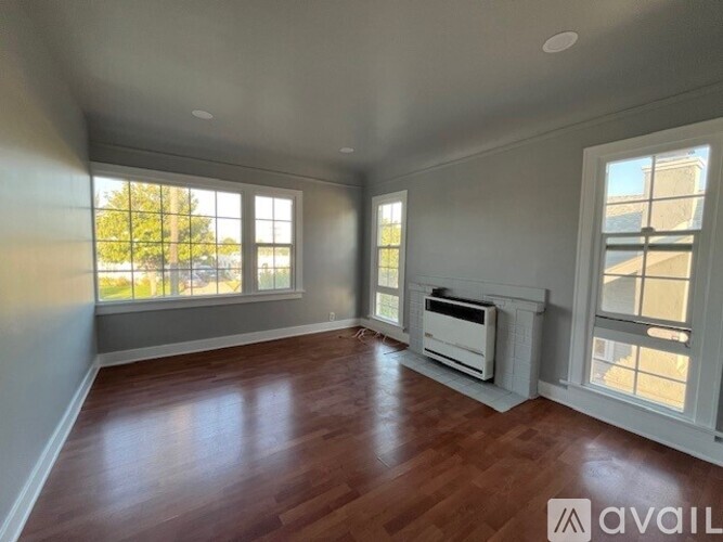 A spacious room with wooden floors and large windows.