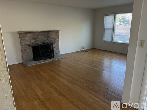A living room with a fireplace and wood flooring.
