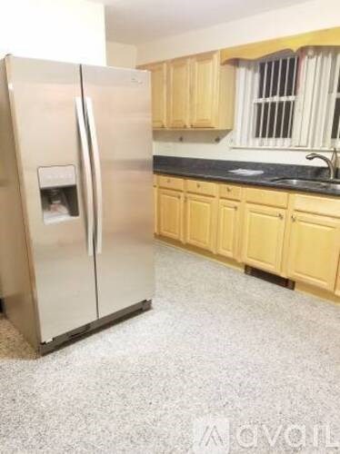 A kitchen with a refrigerator, cabinets, and a window.