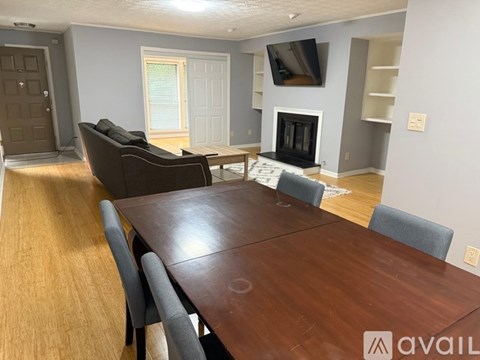 A living room with a brown table and grey chairs.