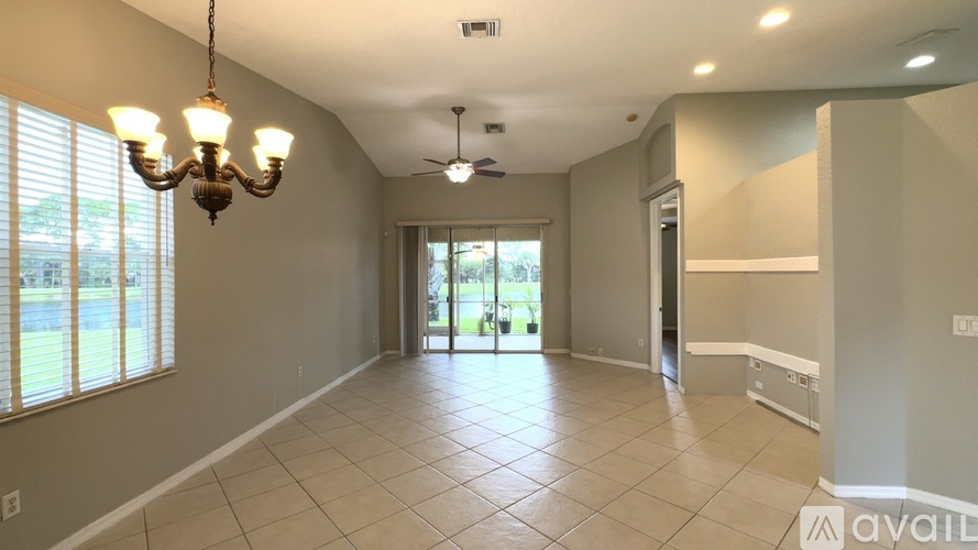 A spacious room with a chandelier, ceiling fan, and sliding glass doors.