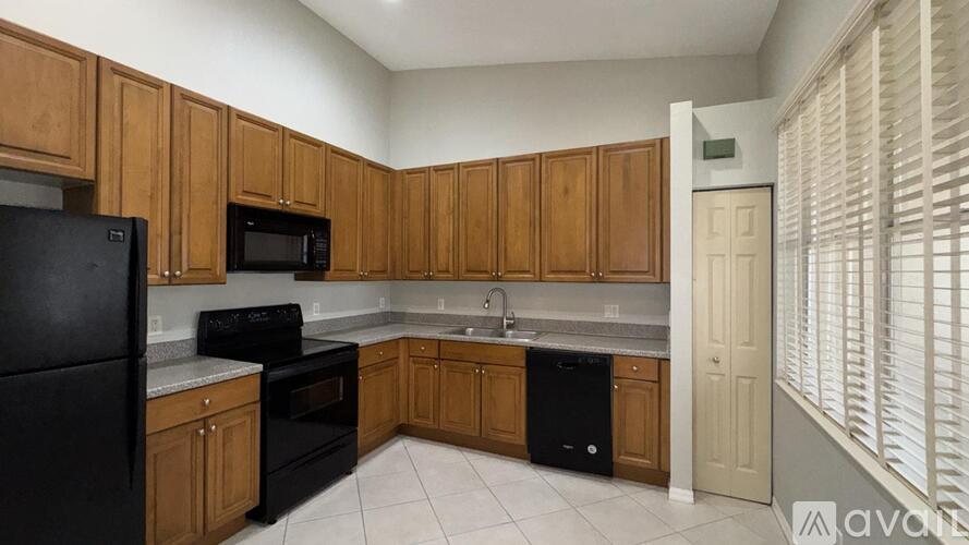 A kitchen with black appliances and wooden cabinets.