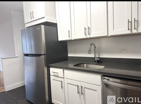 A kitchen with white cabinets and a stainless steel refrigerator.