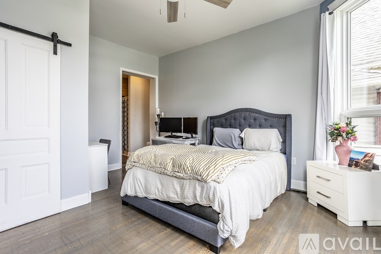 A bedroom with a large bed and a dresser with a vase of flowers on top.
