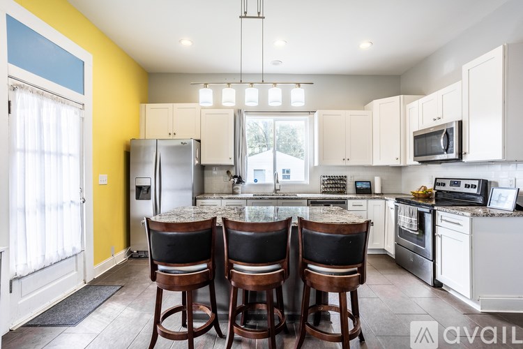 A kitchen with white cabinets and a yellow wall.