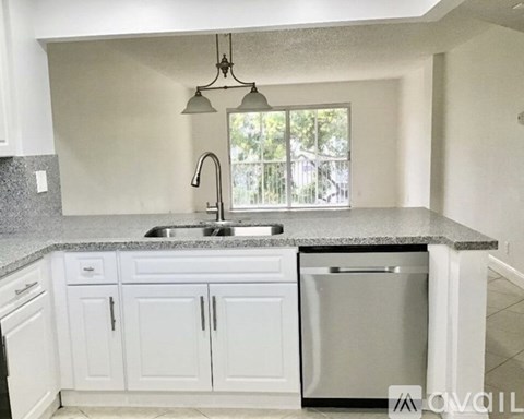 A kitchen with white cabinets and a granite countertop.