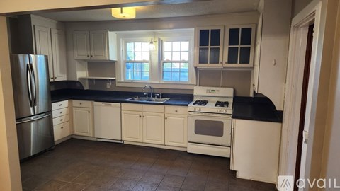 A kitchen with white cabinets and a black countertop.