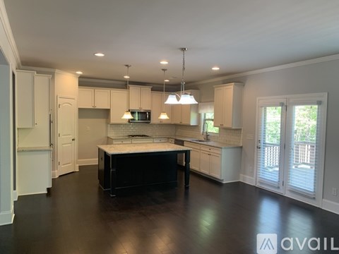 A kitchen with white cabinets and a black island.