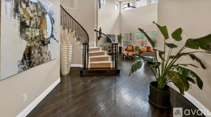 A living room with a staircase and a large painting on the wall.