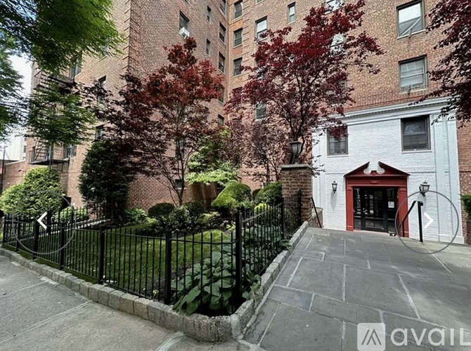 A black metal fence surrounds a brick building with a red door.